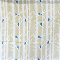 Fabric with white tree branches and blue birds pattern on a beige background