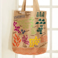 Tote bag with colorful floral design hanging on a white door