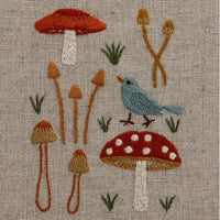 Embroidered design of mushrooms and a bird on textured fabric
