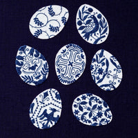 A dark navy blue fabric featuring seven white Easter eggs with various blue traditional floral and bird patterns, arranged in a circle. Small text at the bottom reads 'Easter Eggs | page 77'.