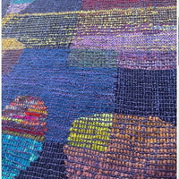 Multicolored woven fabric with a geometric pattern on a textured surface.