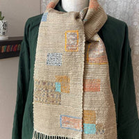 Textile scarf with geometric pattern draped over a green garment, close-up on fabric texture.