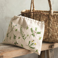 Woven basket and embroidered fabric on a wooden surface with a neutral background