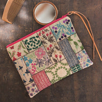 Patchwork pouch with floral and geometric patterns on a wooden surface with a comb and small container.