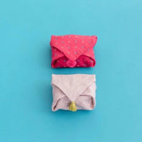 Two folded clothes, one red and one gray with a yellow tag, on a blue background