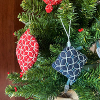 Decorative Christmas ornaments on a tree with a red heart ornament in the background.