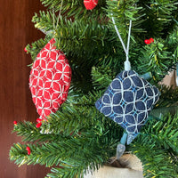 Decorative Christmas ornaments on a tree with a red and white pattern and blue and white pattern.
