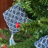 Blue geometric-patterned ornaments hanging on a Christmas tree