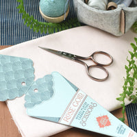 Scissors and packaging on a wooden surface with greenery