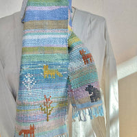 Colorful woven scarf with animal designs on a mannequin against a neutral background
