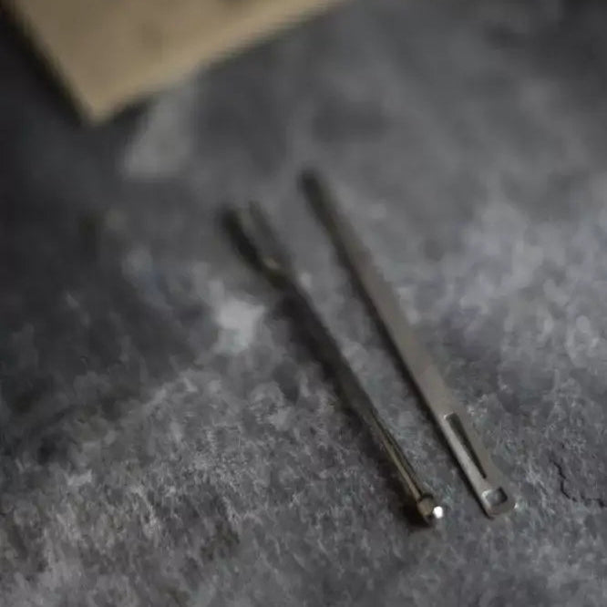 Two metal tools on a textured gray surface with a blurred background