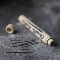 Needle tube and needles on a textured dark surface