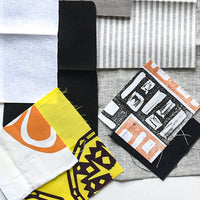Collection of fabric swatches with various patterns and colors on a textured surface.