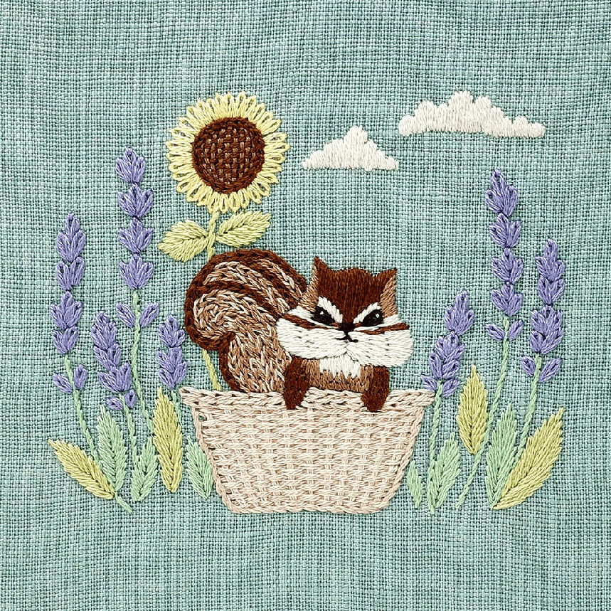 Embroidery design with a chipmunk in a basket surrounded by sunflowers and lavender on a textured background.