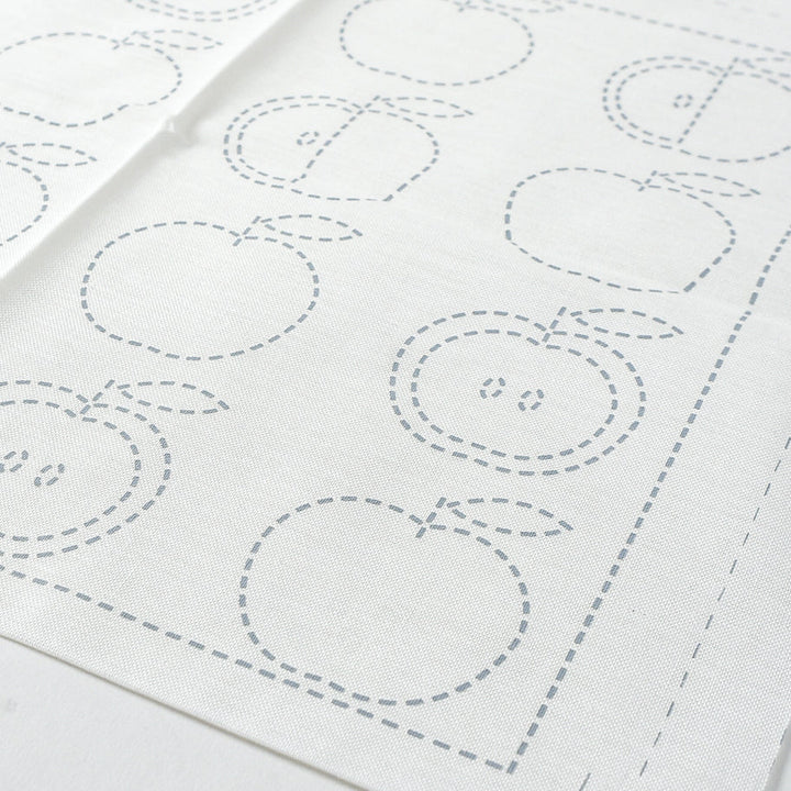White fabric with apple-shaped outlines on a white background