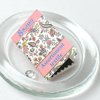 Packaged needles with floral design and text on a clear glass plate