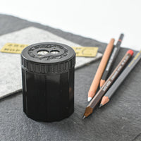 Black pencil sharpener with sharpened pencils on a gray surface