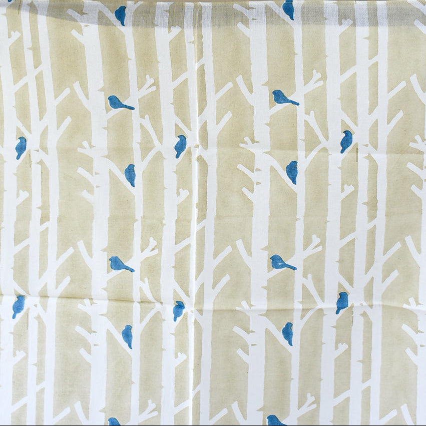 Fabric with white tree branches and blue birds pattern on a beige background