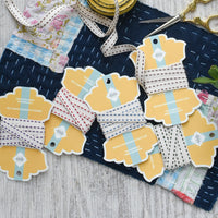Spools of ribbon with decorative tags on a textured surface
