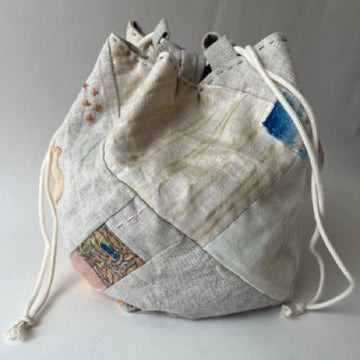Drawstring bag with patchwork design on a light gray background