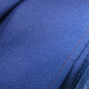 Close-up of blue fabric with red stitching on a spool.