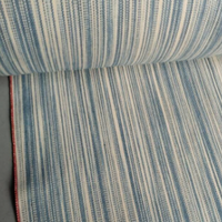 Roll of blue and white striped fabric on a gray surface
