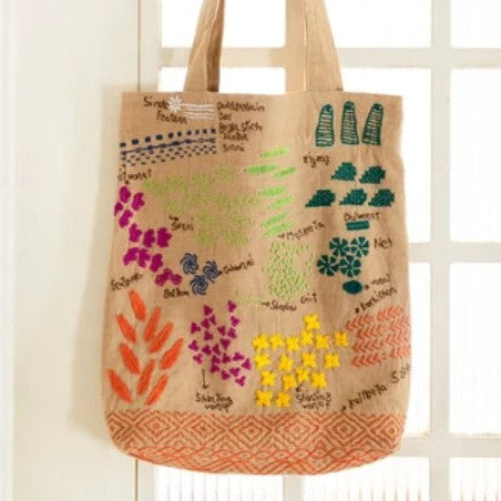 Tote bag with colorful floral design hanging on a white door