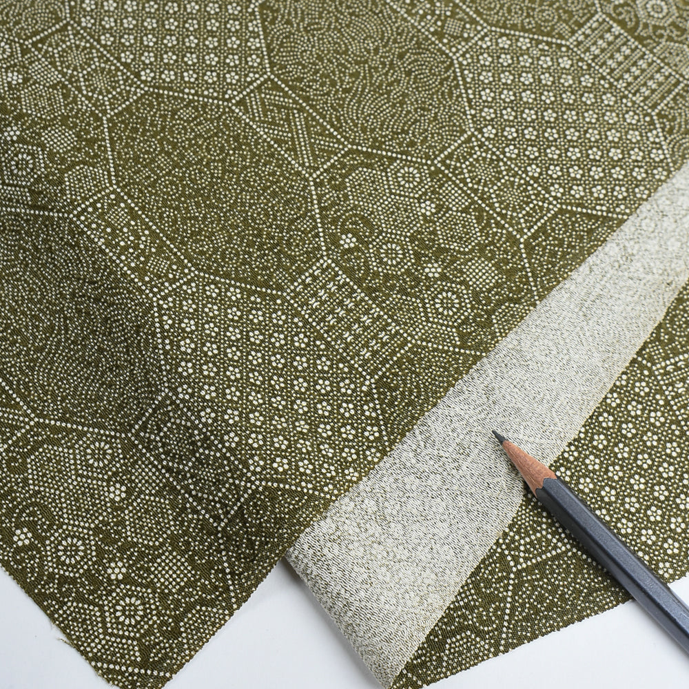 Green patterned paper with a pencil on a white background