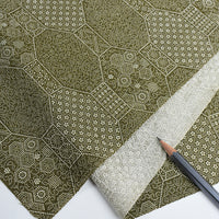 Green patterned paper with a pencil on a white background