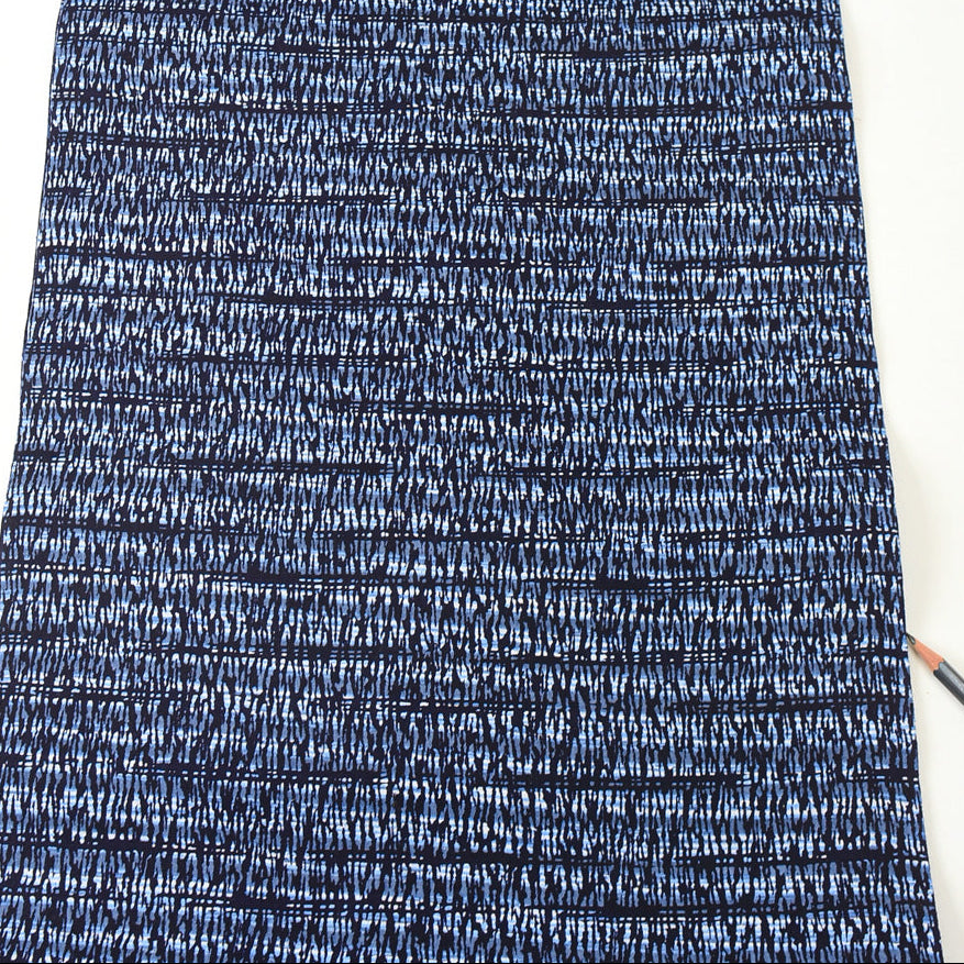 Close-up of blue and white textured fabric with a pencil on a white background