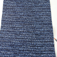 Close-up of blue and white textured fabric with a pencil on a white background