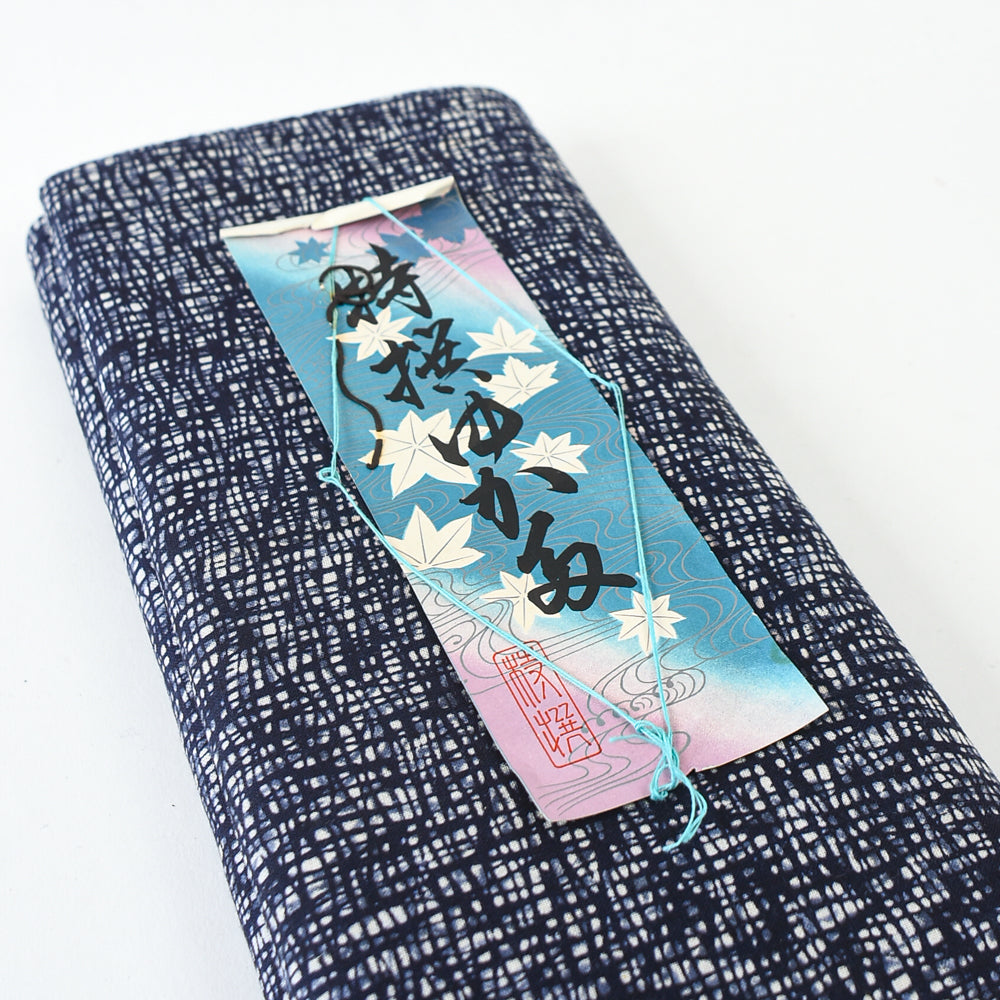 Blue and white patterned fabric with a decorative tag on a white background