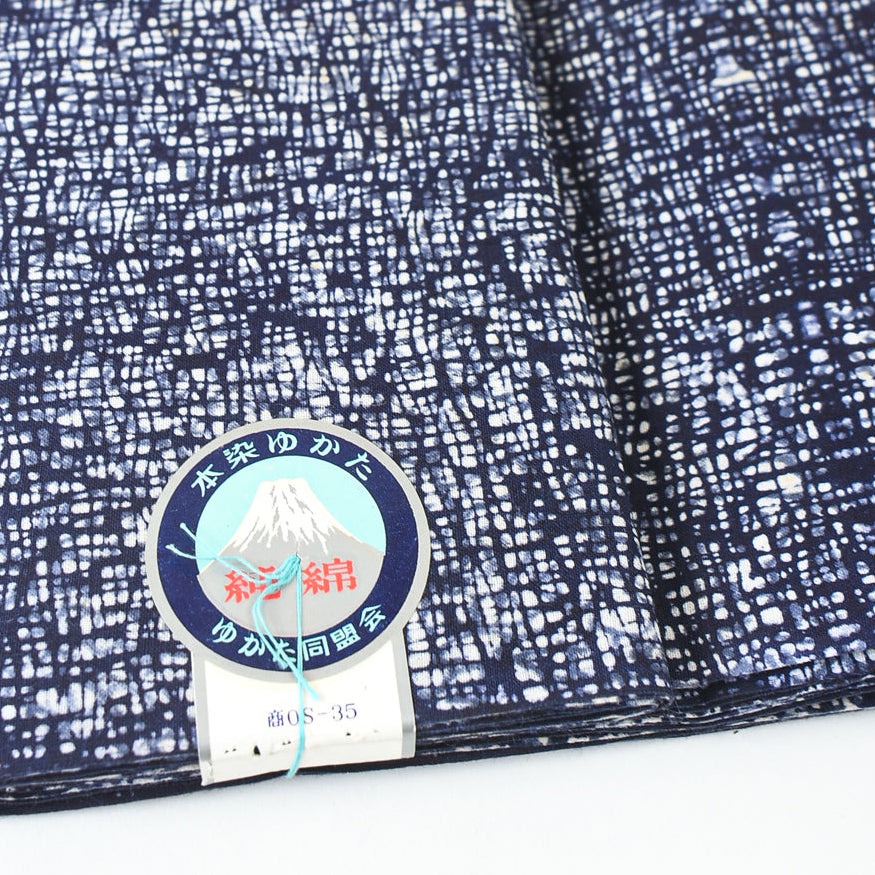 Close-up of blue and white fabric with a label featuring a mountain design.