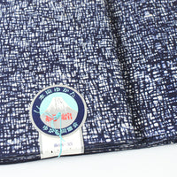 Close-up of blue and white fabric with a label featuring a mountain design.
