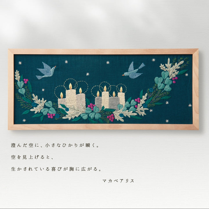 Framed embroidered artwork with candles and birds on a dark blue background