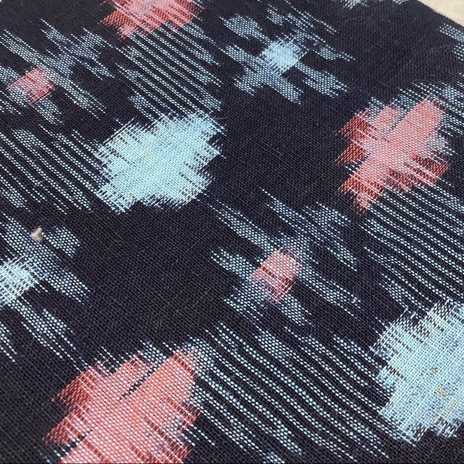 Close-up of fabric with red and blue abstract pattern on black background