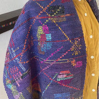 Colorful woven fabric on a yellow garment with a plain background