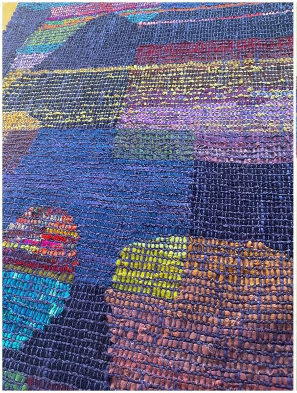 Multicolored woven fabric with a geometric pattern on a textured surface.