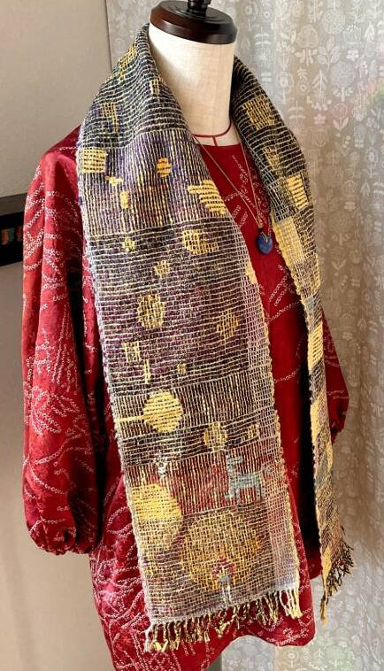 Red garment with a patterned scarf draped over a mannequin against a neutral background