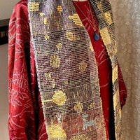 Red garment with a patterned scarf draped over a mannequin against a neutral background