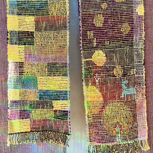 Colorful woven scarf on a wooden hanger against a textured brown background