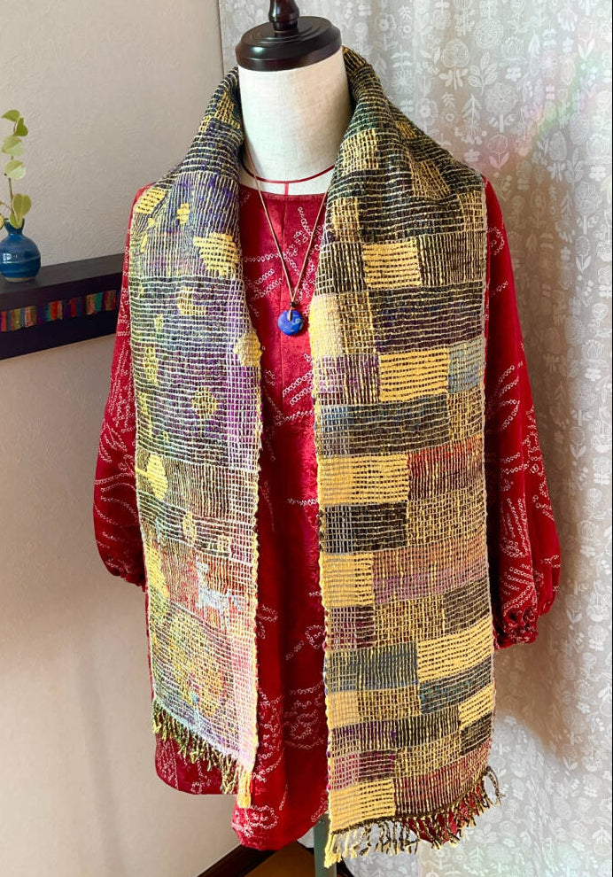 Mannequin wearing a red jacket and colorful patterned scarf against a neutral background