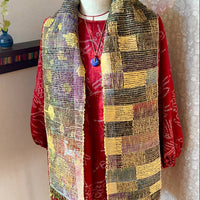 Mannequin wearing a red jacket and colorful patterned scarf against a neutral background