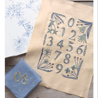 Embroidered fabric with numbers and floral patterns on a wooden surface