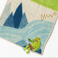Green towel with a frog and mountain design on a white background