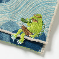 Embroidered green frog on a textured blue and white fabric