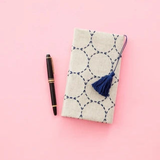 Notebook with a tassel and pen on a pink background