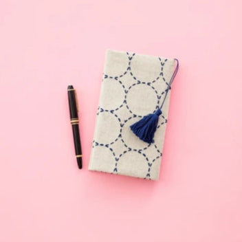 Notebook with a tassel and pen on a pink background