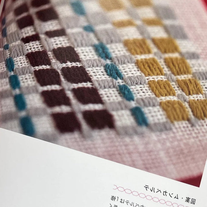 Open book showing cross-stitch patterns on fabric
