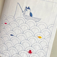 Open book showing illustrations of cat and fish patterns on fabric